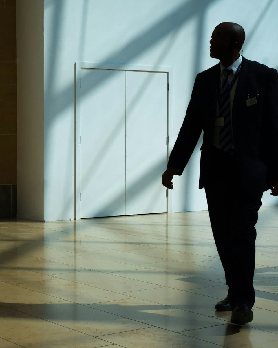 Beveiliger loopt door een hal met invallend licht